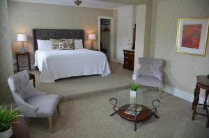 a bedroom with a bed and two chairs and a table at Maplewood Hotel in Saugatuck