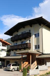 un bâtiment avec balcon et voitures garées dans un parking dans l'établissement Appartements Konrad, à Söll