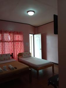 a room with two beds and a window at Alona KatChaJo Inn in Panglao