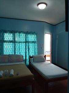 a blue room with two beds and a window at Alona KatChaJo Inn in Panglao Island