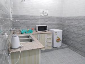 a small kitchen with a sink and a microwave at Dar ALHamra Inn in Al Ḩamrāʼ