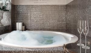 a bathroom with a tub with two wine glasses at Jacuzzi Apartamentai Relaks in Klaipėda