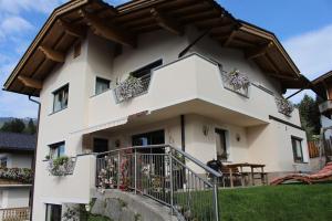 a white house with potted plants and a balcony at Apart Melanie in Zell am Ziller