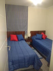 2 camas en una habitación con almohadas azules y rojas en departamento por día Arica, en Arica