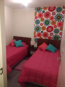 2 camas en una habitación pequeña con sábanas rojas en departamento por día Arica, en Arica
