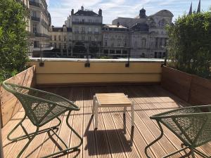 two chairs and a table on a balcony with buildings at Hôtel Saint-Julien in Angers