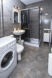 a bathroom with a washing machine and a sink at Apartamenty Sedinum - Brama Portowa in Szczecin