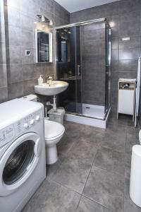 a bathroom with a washing machine and a sink at Apartamenty Sedinum - Brama Portowa in Szczecin +33 photos