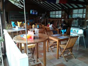 a restaurant with wooden tables and chairs with people in the background at Villa Obaki in Sainte-Anne