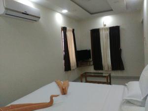 a room with a bed and a window and a television at Sri Nivas Guest House in Mayiladuthurai
