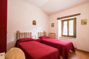 two beds in a room with red sheets at Villa Valdarecchia in Apecchio