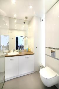a white bathroom with a toilet and a sink at Calamo Park, Apartamenty z klimatyzacją in Olsztyn