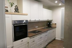 eine Küche mit weißen Schränken, einer Spüle und einer Mikrowelle in der Unterkunft Sauerland Juwel in Olsberg