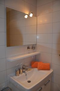 a bathroom sink with a mirror and an orange towel at Ferienwohnung Familie Böckmann auf Norderney in Norderney