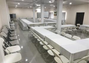 a room with white tables and chairs and a screen at Hotel Cabenda in Freetown