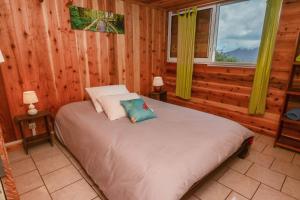 um quarto com uma cama num chalé de madeira em Le Chalet à Joel em Cilaos