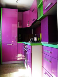 ポズナンにあるBukowska Apartmentのピンクのキッチン(紫色のキャビネット、電化製品付)