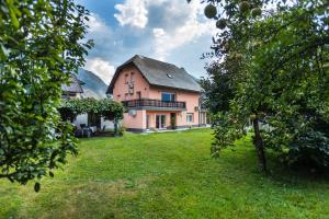 a large pink house with a grass yard at Apartment Japka in Bovec