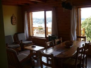 a dining room with a table and chairs and a window at Cabañas Bahia Radal in Villa Pehuenia