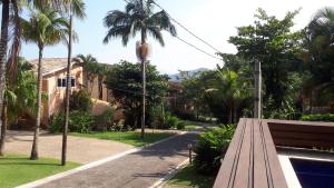 Casa em Toque Toque Pequeno في باوبا: حديقة فيها جلسة و نخيل على شارع