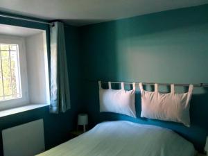 a blue bedroom with a bed with pillows and a window at 7 Rue du Docteur Paul Jouve in Digne-les-Bains