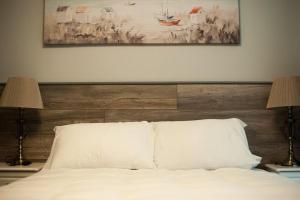 a white bed with two lamps and a painting above it at Sinnotts Bar in Wexford