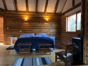 a bedroom with a bed in a log cabin at Laguna Larga Lodge in Parque Nacional Los Alerces