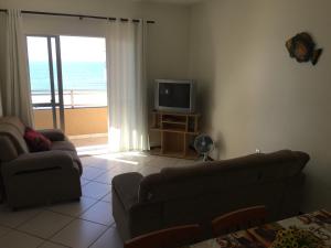 sala de estar con sofá, TV y balcón en PraiaMar Apartamentos, en Itapema