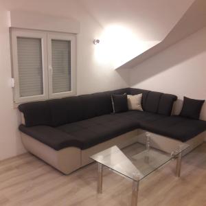 ein Wohnzimmer mit einem schwarzen Sofa und einem Glastisch in der Unterkunft M&A in Trebinje