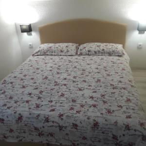 Bett mit Blumenbettdecke und 2 Kissen in der Unterkunft M&A in Trebinje