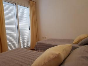 a bedroom with two beds and a window with shutters at Araceli in Famara
