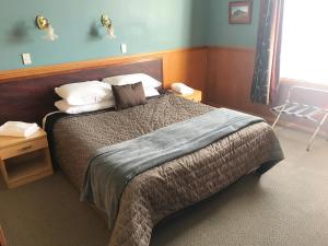 
a bedroom with a bed and a dresser at The Pier Hotel in Kaikoura
