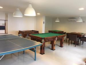 una sala con tavoli da ping pong e sedie di Apartamento 01 Enseada Praia do Forte a Praia do Forte