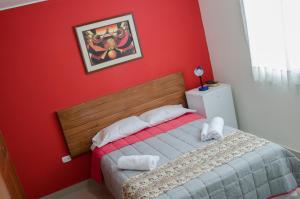 a bedroom with a red wall and a bed with towels at Jazmines Lodging in Ica