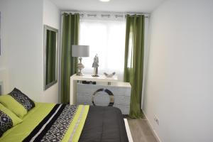 1 dormitorio con 1 cama con cortinas verdes y ventana en Happy House, en Ponta Delgada