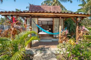 uma pequena casa com uma rede de descanso num jardim em Coconut Garden Resort em Gili Trawangan