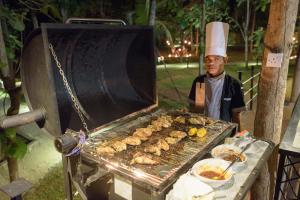 a man is cooking food on a grill at Kottawatta Village in Udawalawe
