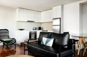 a living room with a black leather couch and a kitchen at Veriu Randwick in Sydney