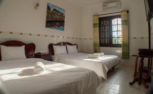 a bedroom with two beds and a window at DK's Backpacker Hotel in Hoi An