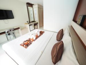een slaapkamer met een bed met witte lakens en een televisie bij Lanta Fevrier Resort in Koh Lanta