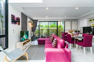 a living room with pink furniture and a kitchen at Pause on Samui Residences in Bophut