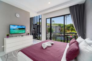 a bedroom with a bed and a tv and a balcony at Pause on Samui Residences in Bophut 