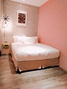 a large bed in a room with a pink wall at King Wow Inn in Tainan