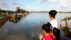 a man and two little girls standing next to a river at Homestay Memori in Dungun