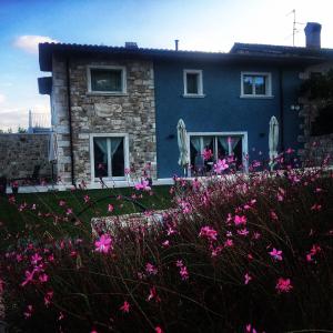 una casa azul con flores rosas delante en Residenza Case Pacifici en Ascoli Piceno