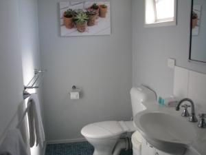 a white toilet sitting next to a sink in a bathroom at Charm City Motel in Bundaberg