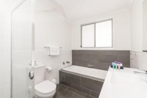 a white toilet sitting next to a bath tub in a bathroom at Wallsend on Longworth in Newcastle
