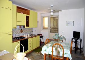 Villetta Anna في توري فادو: مطبخ مع دواليب صفراء وطاولة مع كراسي +5 صور