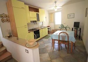 Villetta Anna في توري فادو: مطبخ فيه دواليب صفراء وطاولة وكراسي