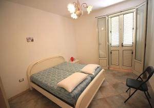 Villetta Anna في توري فادو: غرفة نوم بها سرير وكرسي